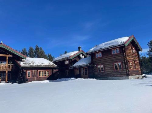 a large wooden house with snow on its roof at Rondane Sollia Friluftsliv Øvre Nordli in Sollia