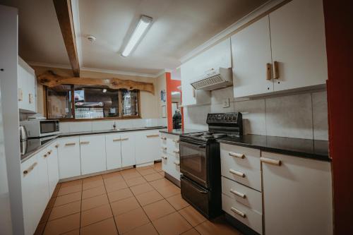 una cucina con armadi bianchi e un forno a piano cottura nero di Storms River Forest Lodge a Stormsrivier