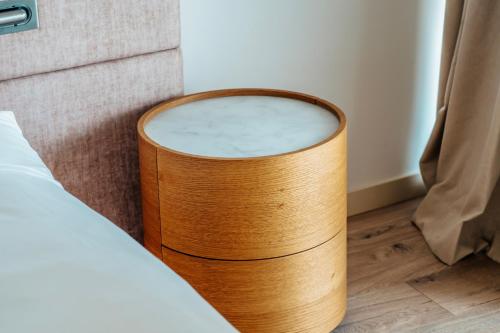 a wooden stool next to a bed in a room at Green Cape Botanico in Batumi
