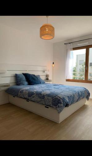 une chambre avec un lit avec une couette bleue et une fenêtre dans l'établissement Le moderne boisé Disneyland Paris 10 min ' Parking, à Montévrain