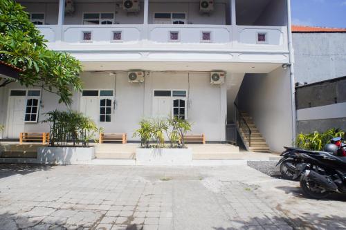 a building with two benches and a motorcycle parked in front at Fun Living Guest House in Seminyak