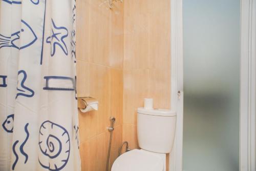 a bathroom with a toilet and a shower curtain at Fun Living Guest House in Seminyak
