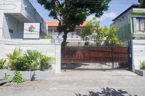 a gate in front of a house with a tree at Fun Living Guest House in Seminyak