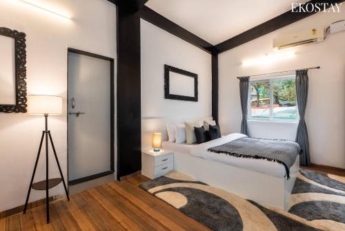 a bedroom with a bed and a window at EKOSTAY Gold - White Swan Villa 6BHK in Panchgani