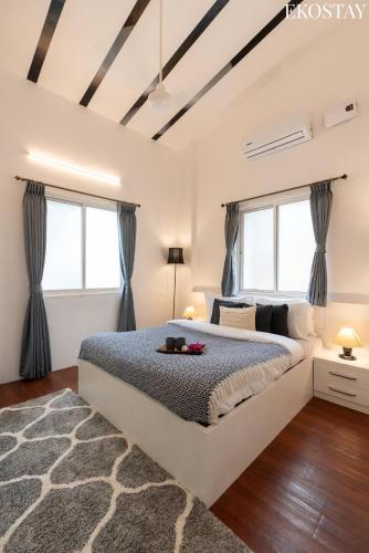 a bedroom with a large bed and two windows at EKOSTAY Gold - White Swan Villa 6BHK in Panchgani