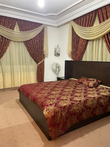a bedroom with a large bed with curtains and a fan at Shafa Badran Villa in Amman