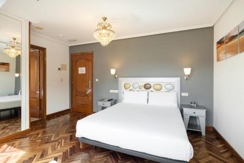a bedroom with a white bed and a chandelier at Hotel Alda Santa Cristina in Perillo