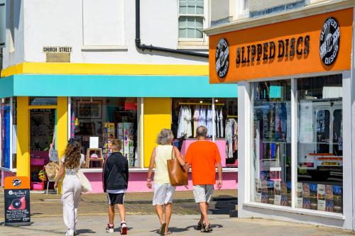 people walking down a street in front of a store at Modern Seaside Townhouse feat Sauna near Brighton in Shoreham-by-Sea