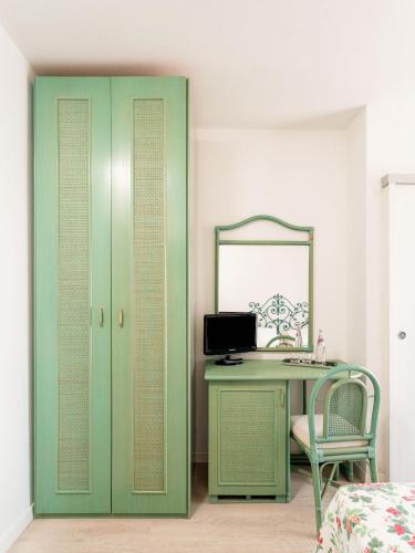 a bedroom with a desk with a mirror and a green cabinet at Hotel Sonia in Forte dei Marmi