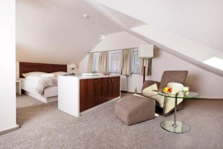 a bedroom with a bed and a chair and a table at Restaurant Niedmühle Land & Genuss Hotel in Rehlingen-Siersburg