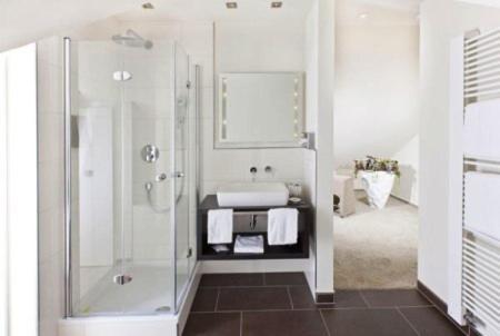 a white bathroom with a shower and a sink at Restaurant Niedmühle Land & Genuss Hotel in Rehlingen-Siersburg