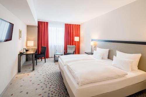 a hotel room with a large bed and a desk at Steigenberger Hotel Bielefelder Hof in Bielefeld