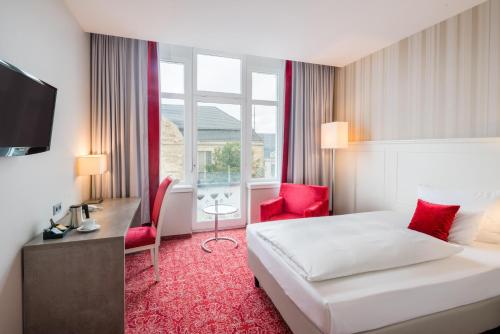 a hotel room with a bed and a desk at Steigenberger Hotel Bielefelder Hof in Bielefeld