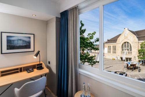 a room with a desk and a large window at Steigenberger Hotel Bielefelder Hof in Bielefeld