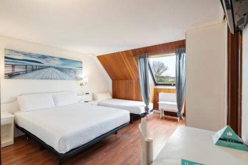 a bedroom with a bed and a chair and a window at Hotel Alda Santa Cristina in Perillo