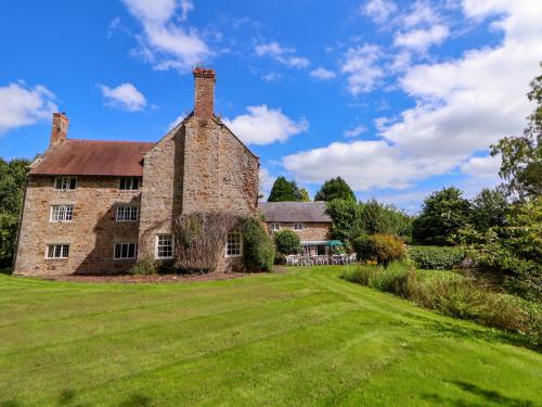 an old stone house with a large grass yard at New Hall in Wrexham