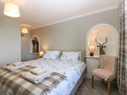 a bedroom with a bed with a blanket and a chair at West Pier Cottage in Macduff