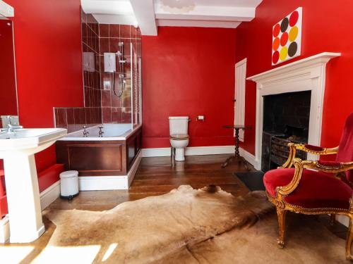 a bathroom with red walls and a dog laying on the floor at New Hall in Wrexham