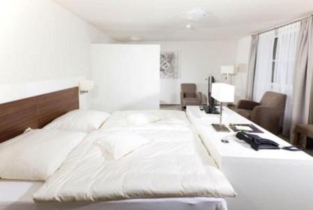a bedroom with a large white bed and a desk at Restaurant Niedmühle Land & Genuss Hotel in Rehlingen-Siersburg