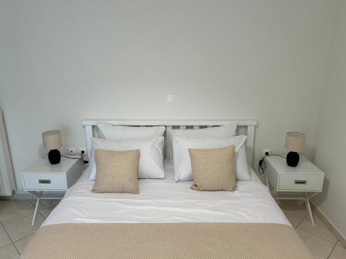 a white bed with white pillows and two night stands at Mesogaia Home Near ATH Airport in Markopoulo