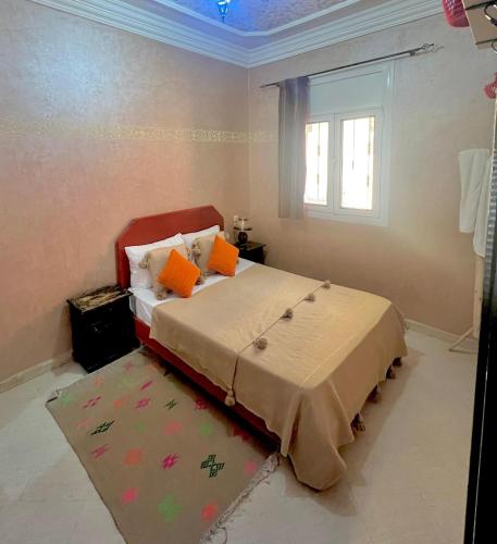 a bedroom with a bed with orange pillows and a rug at Original Surf Morocco in Tamraght Ouzdar