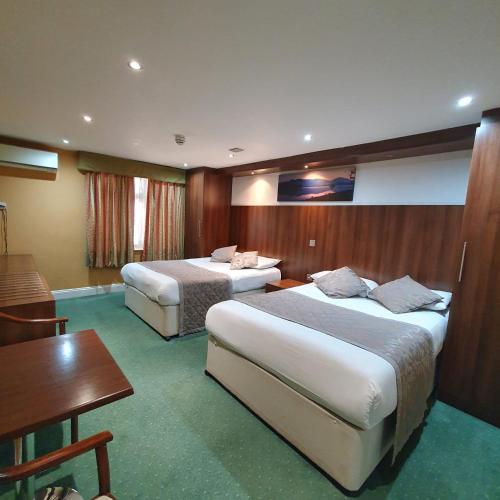 a hotel room with two beds and a table at Hotel Oliver, 198 Cromwell Road SW50SN in London