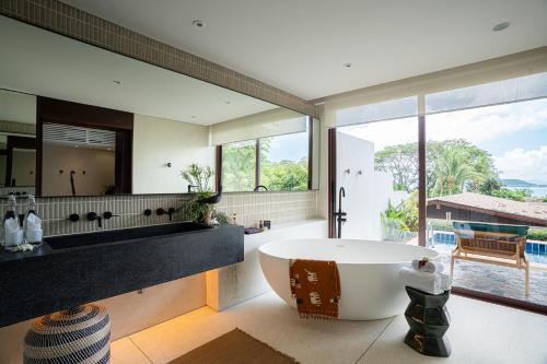 a bathroom with a large tub and a large window at Barcelo Coconut Island, Phuket in Phuket Town