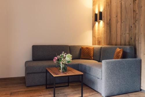 a living room with a couch and a table with flowers at Hotel - Gasthof Märzenklamm in Stumm