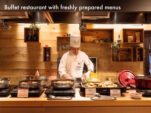 a chef is preparing food in a kitchen at Hotel Naturwald Furano in Furano