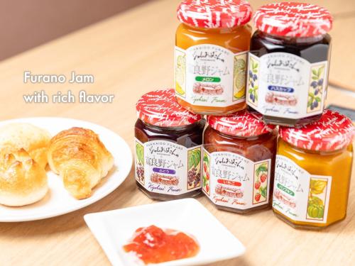 a table topped with jars of jam and a plate of bread at Hotel Naturwald Furano in Furano
