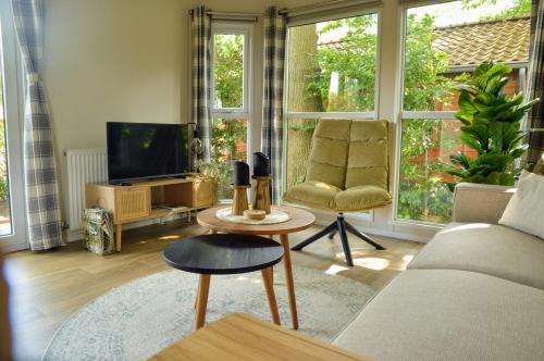 a living room with a couch and a tv at Gezellig vakantiechalet in bosrijke omgeving op de Veluwe in Epe