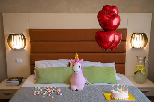 a bed with a unicorn and a cake and balloons at MBI Travel Inn in Craiova