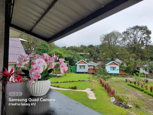 a vase of pink flowers on a table with a garden at อินทนนท์ เล่าจู in Ban Na Yang