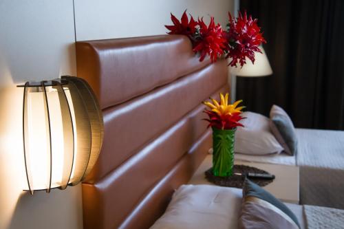 a hotel room with a bed and a vase of flowers on a table at MBI Travel Inn in Craiova
