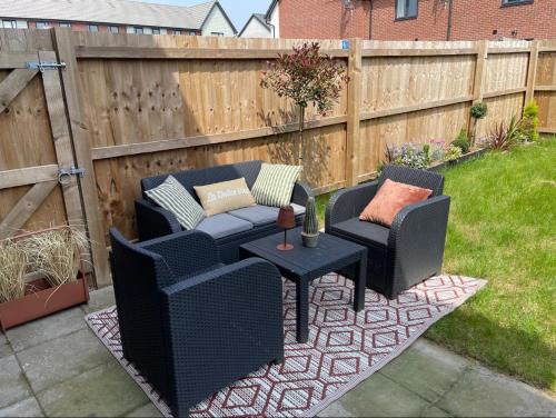 a patio with two chairs and a table and a fence at Barry Waterfront Stays - ENTIRE 3 BED PROPERTY in Barry
