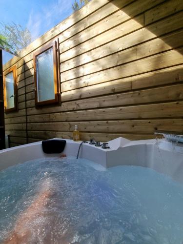 a bath tub in front of a wooden wall at Les Glycines de Monchy- Chambres d'hôtes in Monchy-Humières