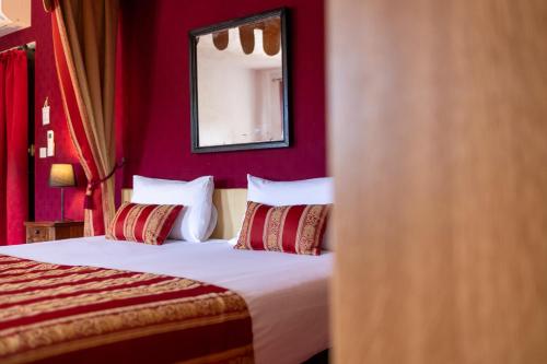 a bedroom with a bed with red walls and a mirror at Château de Trigance in Trigance