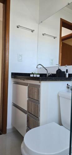 a bathroom with a toilet and a sink and a mirror at Apartamento Confortável Inteligente in Poços de Caldas