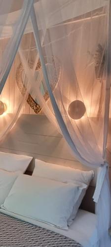 a bed with white curtains and pillows in a room at Les Glycines de Monchy- Chambres d'hôtes in Monchy-Humières