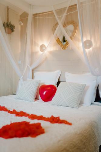 a bedroom with a white bed with a red heart on it at Les Glycines de Monchy- Chambres d'hôtes in Monchy-Humières