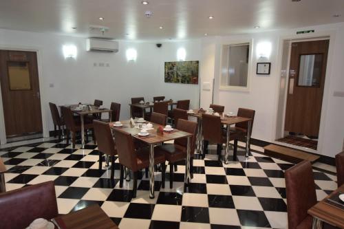 a restaurant with tables and chairs on a checkered floor at Lucky 8 Hotel in Ilford