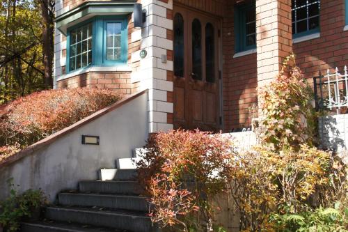 a brick house with stairs leading to a door at Landhaus Dancru Netz in Hakuba