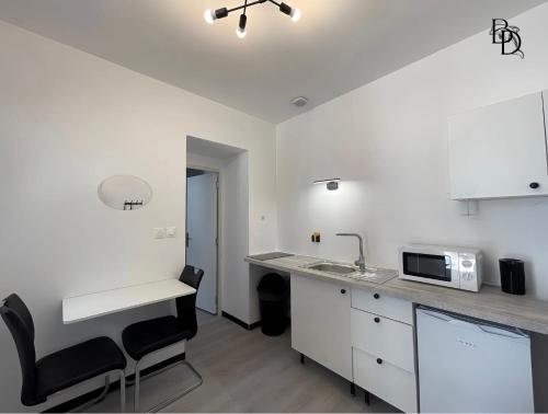 une cuisine blanche avec un évier et un micro-ondes dans l'établissement T1 Bis A3 30m2 Cosy 7min à pieds Gares appartement, à Roanne