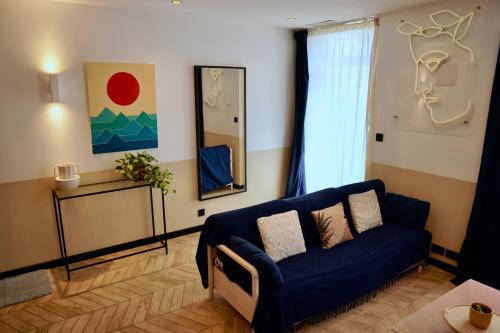 a living room with a blue couch and a mirror at Roma Divine home cinéma et jardin in Nîmes