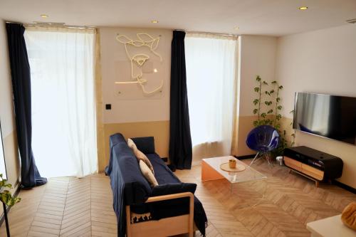 a living room with a blue couch and a tv at Roma Divine home cinéma et jardin in Nîmes