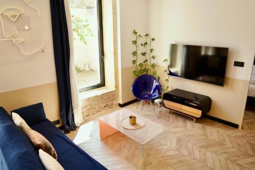 a living room with a blue couch and a tv at Roma Divine home cinéma et jardin in Nîmes