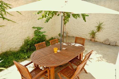 a wooden table with chairs and an umbrella at Roma Divine home cinéma et jardin in Nîmes