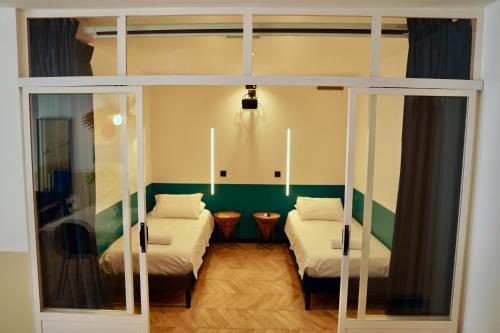 a room with two beds and a glass door at Roma Divine home cinéma et jardin in Nîmes