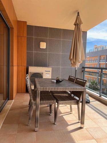 a table and chairs and an umbrella on a balcony at Birds House - Village Marina in Olhão