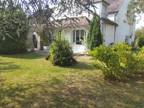 a white house with a bench in the yard at Les Ecureuils in Bougligny